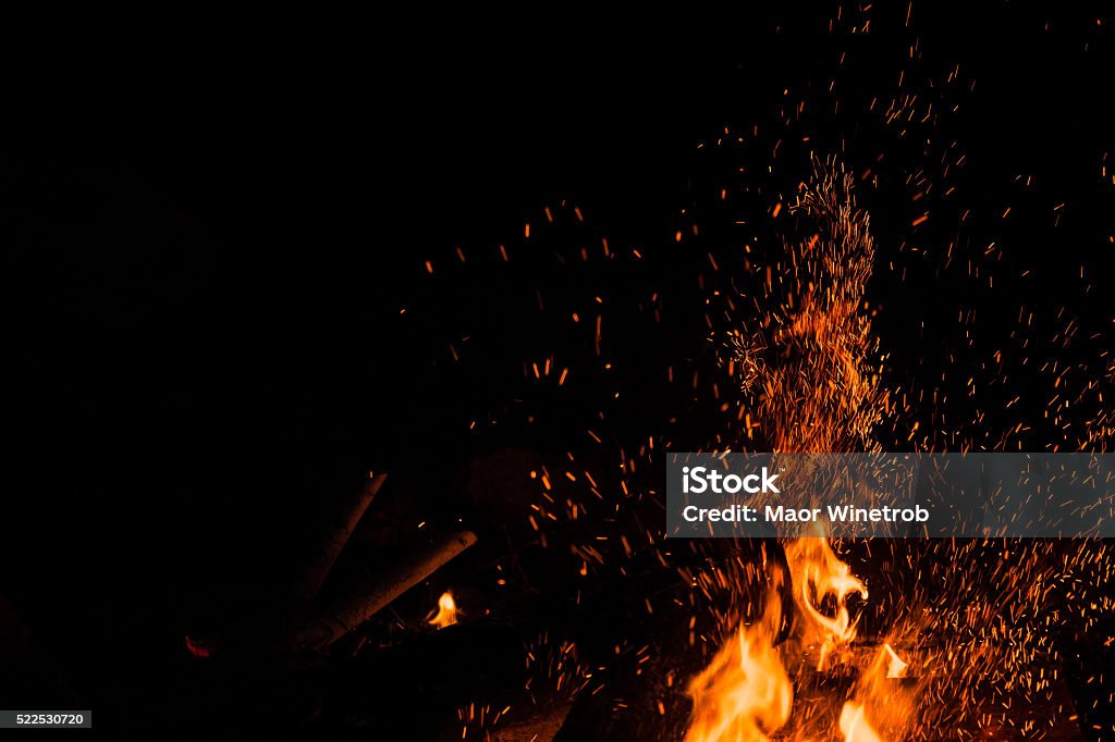 Sparks bounce off from a bonfire at night Sparks bounce off from a bonfire at night after a log thrown into it. Fire - Natural Phenomenon Stock Photo