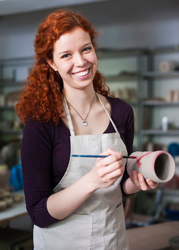 Young woman potter working on a clay vase at workshop