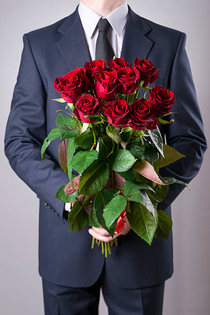 istock Man with bouquet of red roses on a gray background 522532364