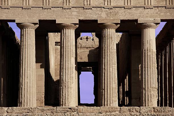 Ancient columns of Hercules Temple at Italy, Sicily, Agrigento. Greek Temples Valley with city background.