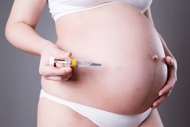 jeune femme enceinte faisant injection dans le ventre - frustration women threats disappointment photos et images de collection