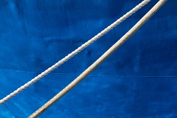 Two white mooring ropes & a Mediterranean blue fishing boat (close-up detail). Lots of copy space available.