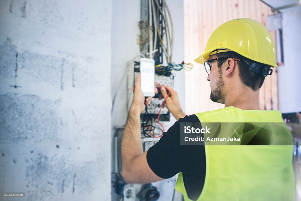 Electrician An electrician fixing up the wires and measuring volts Electricity Stock Photo