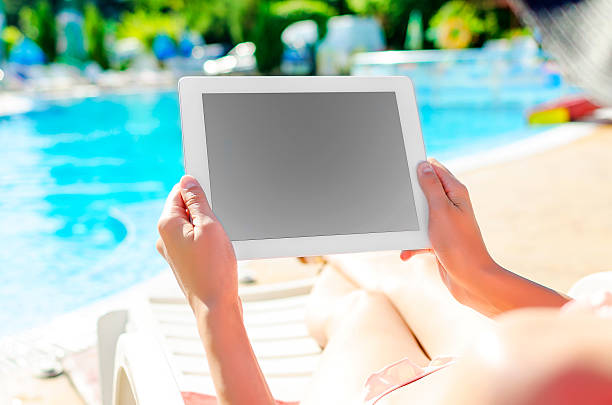 istock With tablet sitting at swimming pool 522540841