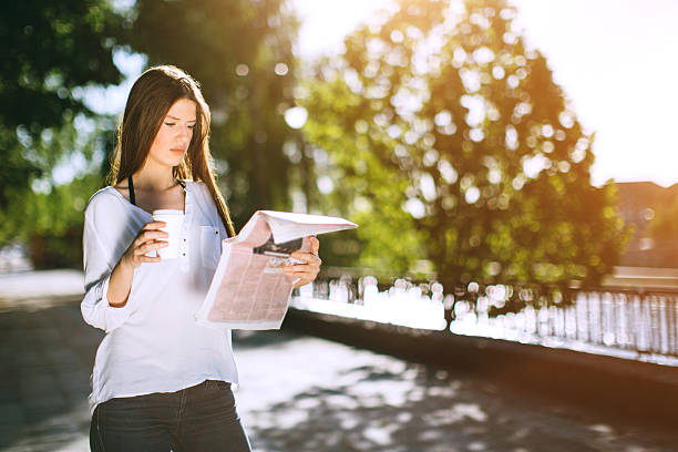 istock young woman reading newspaper and drinking coffee 522540870