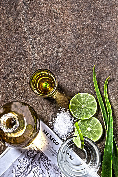 Detail of tequila served in a glass with a slice of lemon and a bottle of tequila isolated on a white background - Close-up