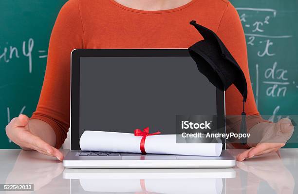 Student Showing Laptop With Mortarboard And Degree In Classroom Stock Photo - Download Image Now