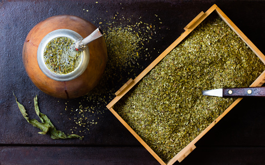 Yerba mate in calabash and wooden box of dry herb.
