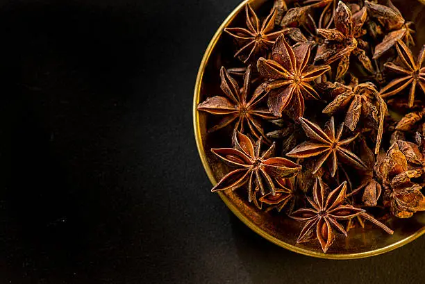 Star shape anis seeds in bowl on black slate background