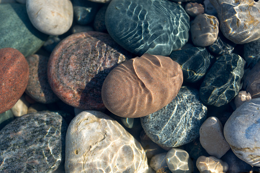 Ripples on the water surface in shallow water with colourful stones.