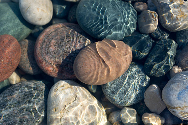 Stones in water Ripples on the water surface in shallow water with colourful stones. pebble stock pictures, royalty-free photos & images