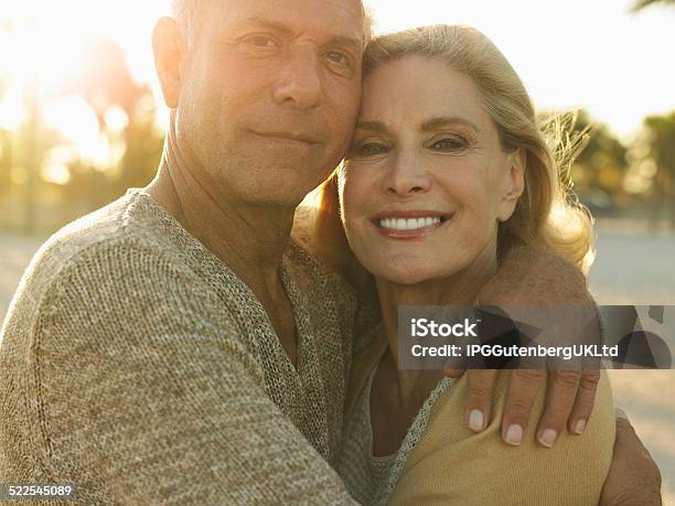 Happy Senior Couple Embracing On Beach Stock Photo - Download Image Now - Active Seniors, Adult, Arm Around