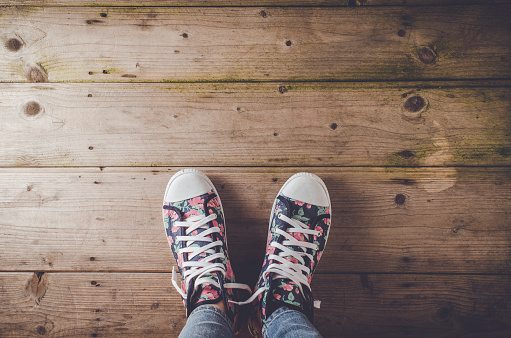 Female sneakers with floral pattern standing on an old wooden floor