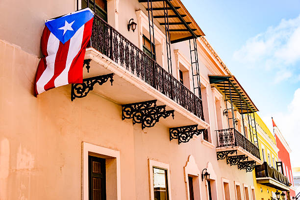 Colorful house facades of Old San Juan, Puerto Rico Colorful house  facades along a street in Old San Juan, Puerto Rico with a Puerto Rican flag hanging down from one of the balconies puerto rico photos stock pictures, royalty-free photos & images