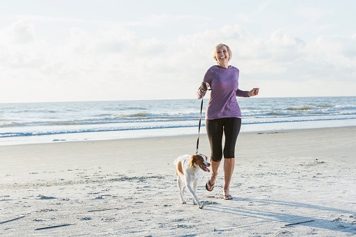 Mature woman walking dog on beach