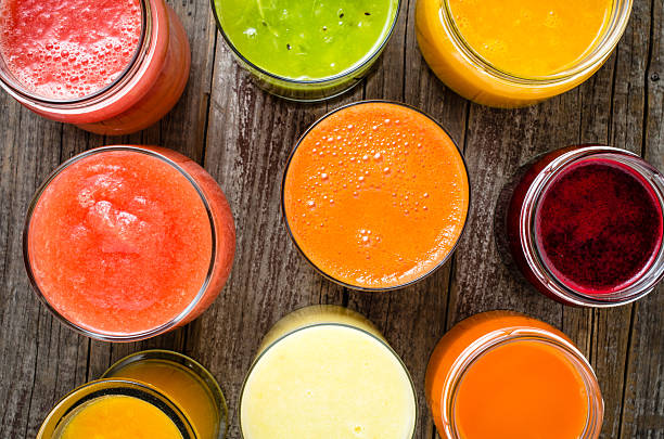 verres de jus de fruits frais sur une tableau en bois - green smoothie vegetable juice fruit photos et images de collection