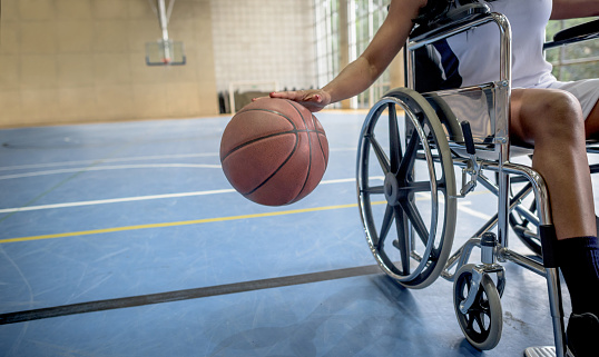 Disabled basketball player bouncing the ball at the court - sports concepts