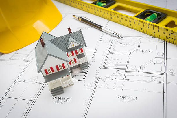istock Home, Level, Hard Hat and Pencil Resting on House Plans 522558528