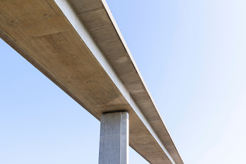Elevated concrete road bridge from below with plain blue sky