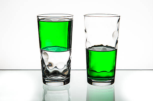 Two glasses, both half-full of green liquid. Half empty or half full - pessimism or optimism half full stock pictures, royalty-free photos & images