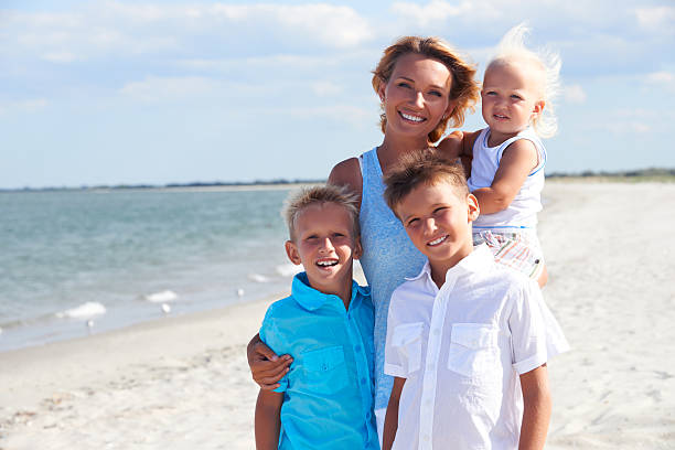 istock Smiling mother with children standing on the beach. 522566705