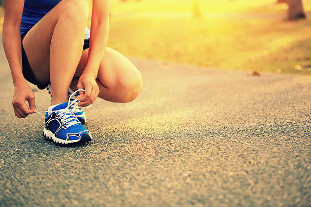 istock woman runner tying shoelaces on trail 522579413