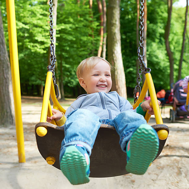istock Happy little blond boy having fun on a swing. 522580331