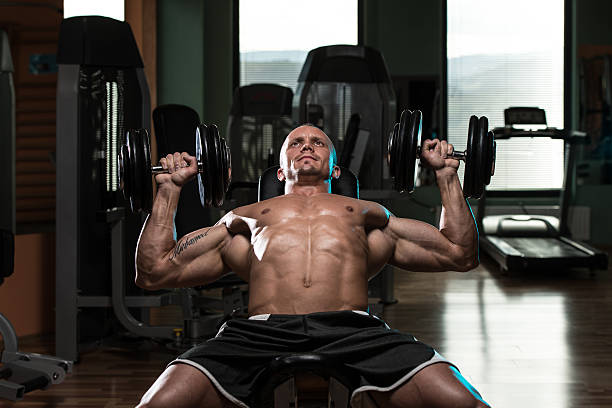 hombre haciendo pesa incline levantamiento de pesas en banco de ejercicios - músculos pectorales fotografías e imágenes de stock