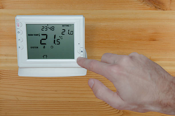 istock Adjusting the temperature with hand to a wireless thermostat 522604967