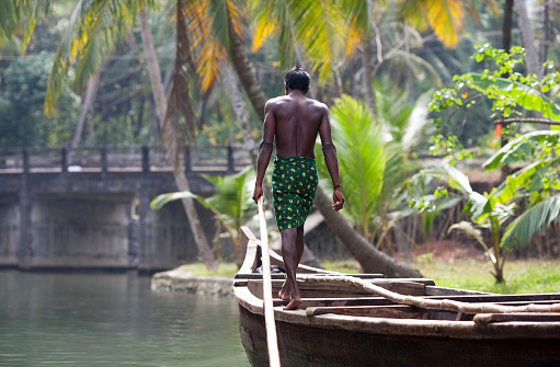 Kollam, Kerala State, India - February 11, 2010: An unidentified Indian boatman floating on the wooden boat in backwaters.
