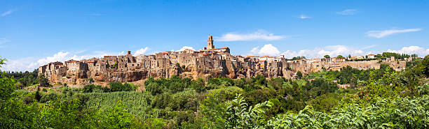 Pitigliano, Tuscany, panorama. Color image Wide-angle panorama of Pitigliano, a town in the Tuscan province of Grosseto, on the border with Lazio. The quaint old town is known as the little Jerusalem, for the presence of an ancient Jewish community. Arriving in Pitigliano you can see the characteristics houses jut out from a large outcrop of tufa cliffs and surrounded on three sides by many gullies, full of caves dug into the tuff. pitigliano stock pictures, royalty-free photos & images