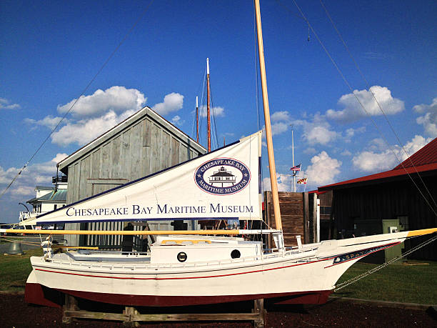 Chesapeake Bay Maritime Museum St. Michaels, Maryland, USA --September 5, 2014:  Chesapeake Bay Maritime Museum in St. Michaels, Maryland on the Miles River on Maryland's Eastern Shore.  Pictured is a restored Chesapeake Bay boat, once used for fishing for oysters, crabs, and other seafood. Photo was taken at the entry to the Maritime Museum on a summer day.  St Michaels is a picturesque historic village on Maryland's Eastern Shore. skipjack stock pictures, royalty-free photos & images