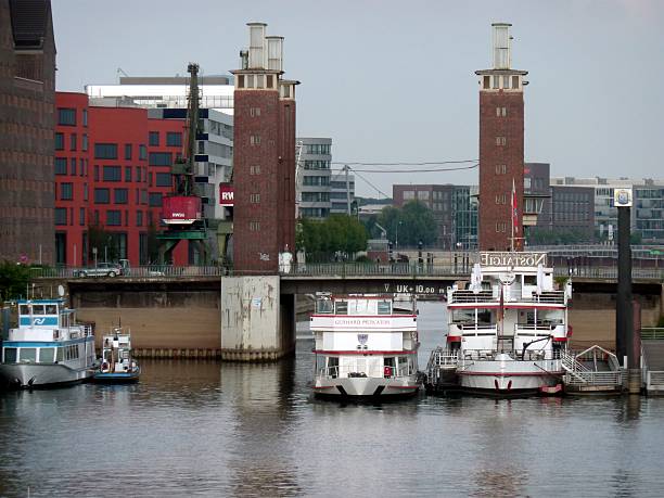 Duisburg, Germany - September 7, 2014: Cruise vessels moored under the historical Schwanentor Bridge, a moving bridge on the Inner Harbour in Duisburg, Germany. Once, during the Industrial Revolution was the central harbour and trading point of the town. It is has now been transformed into a modern district combining employment, housing, culture and on water leisure activities.