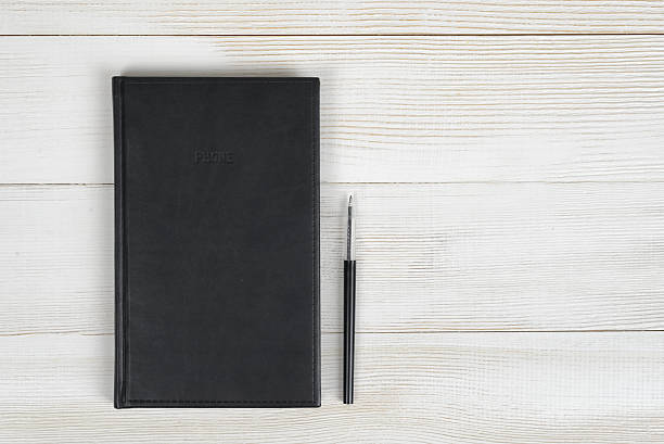 istock Flat lay of black notebook and pen on light wooden 522628422