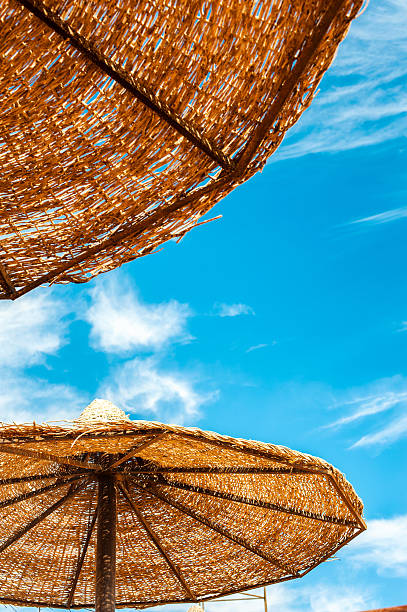 istock Wattled straw beach umbrella on blue cloudy sky background. 522629162