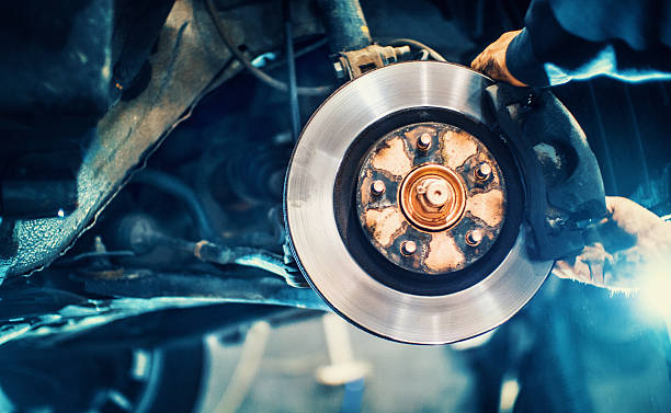 Car service procedure. Closeup of unrecognizable mechanic replacing car brake pads. The car is lifted with hydraulic jack at eye level. brake disc photos stock pictures, royalty-free photos & images