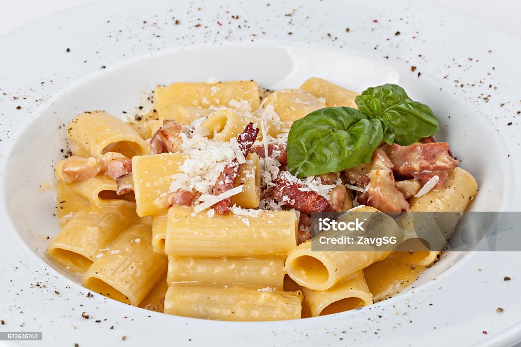 Italian rigatoni pasta with prosciutto, parmesan cheese and leaf Close-up of  italian rigatoni pasta with prosciutto, parmesan cheese and leaf basil. Rigatoni Stock Photo