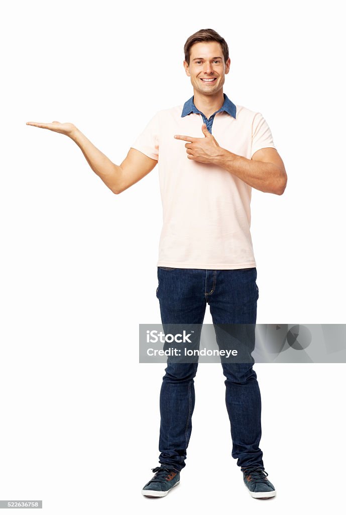 Confident Man Pointing At Invisible Product Full length portrait of confident young man pointing at invisible product over white background. Vertical shot. Arms Outstretched Stock Photo