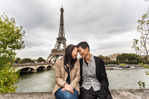A loving romantic Asian couple share an intimate moment at the Eiffel Tower in Paris