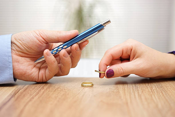 Husband is giving pen to sign divorce papers his wife stock photo