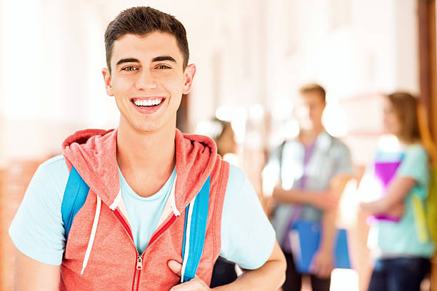 Portrait of happy male student with friends in background at campus. Horizontal shot.