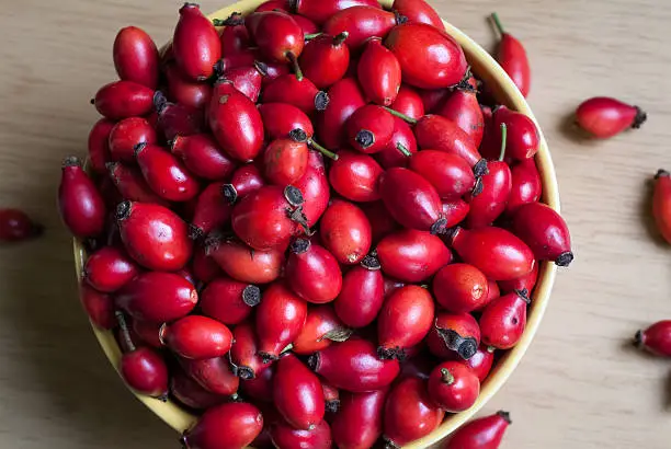 closeup photo of a yellow bowl full of rosehip berries