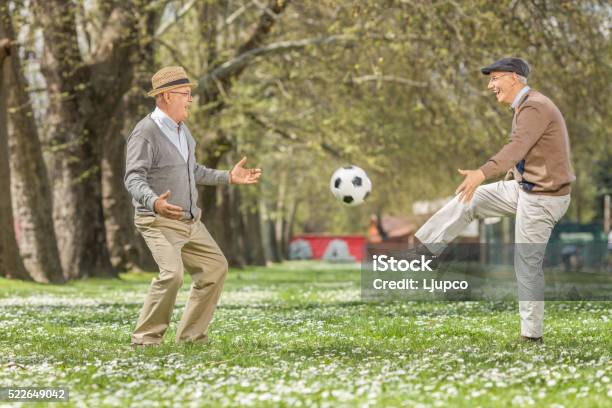 Two Joyful Seniors Playing Football In A Park Stock Photo - Download Image Now - Senior Adult, Agility, Soccer