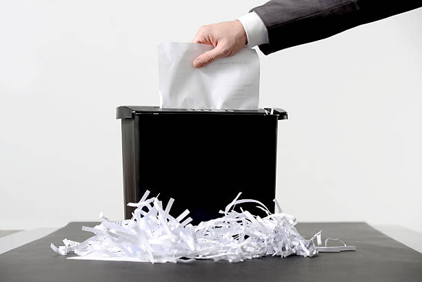 Shredding a paper Hand of businessman putting a document in paper shredder shredded stock pictures, royalty-free photos & images