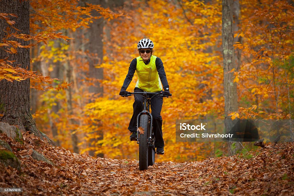 Attractive woman riding a fatbike in the fall An attractive woman in her thirties is riding a colorful trail on her fatbike. Fatbike Stock Photo
