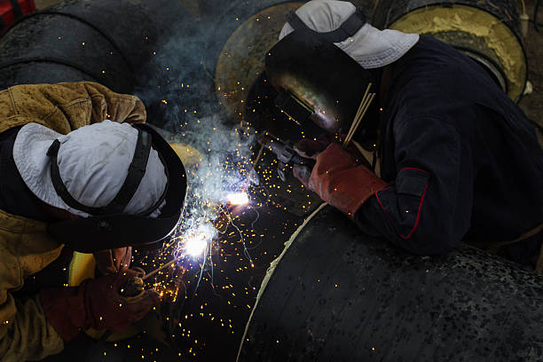 istock Two workers together welding big tube for city heating. 522670311
