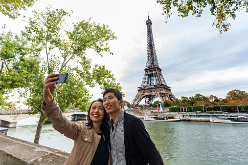 Young Asian couple taking a selfie self portrait at the Eiffel Tower in Paris