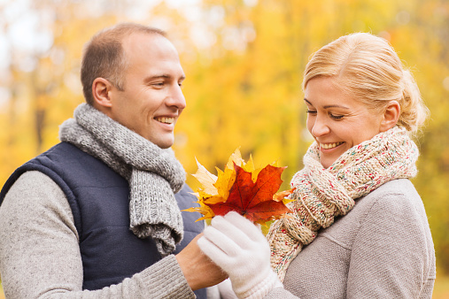 love, relationship, family and people concept - smiling couple with maple leaves in autumn park