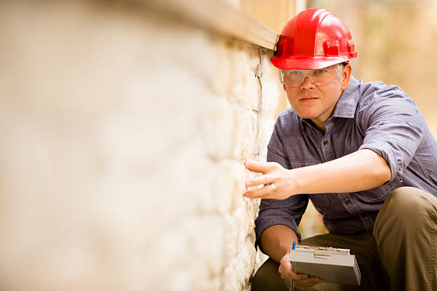 inspector ou construção trabalhador de colarinho azul examina a parede exterior. - home inspection imagens e fotografias de stock