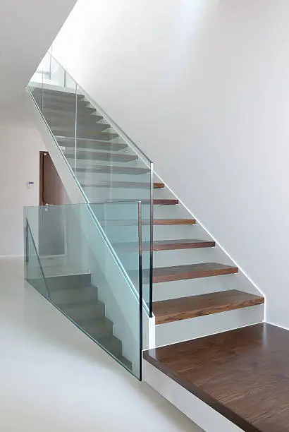 wooden stairs with glass balustrade in modern interior and white epoxy flooring